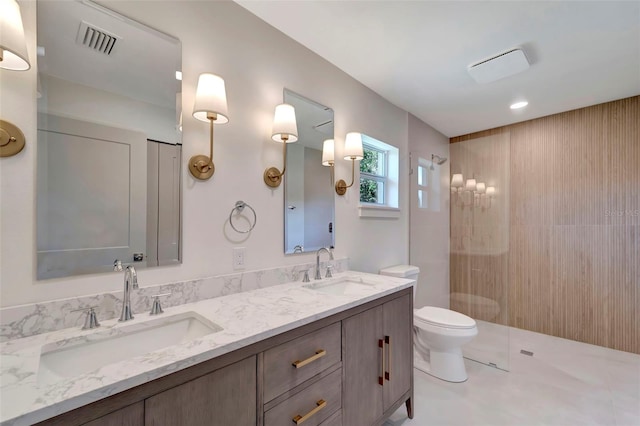 bathroom with tile patterned floors, a tile shower, double vanity, and toilet