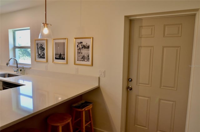 kitchen with hanging light fixtures, a kitchen breakfast bar, and sink