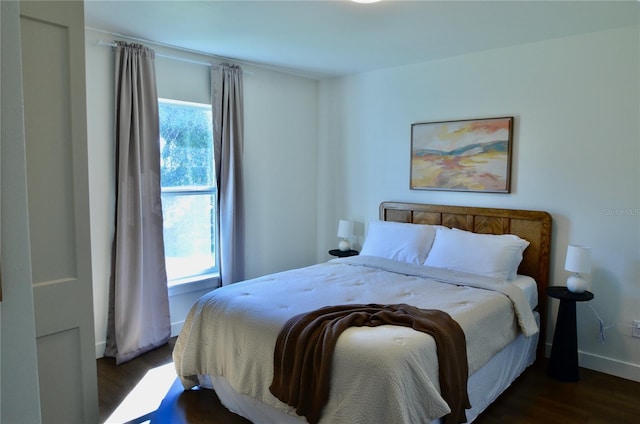 bedroom with multiple windows and dark wood-type flooring