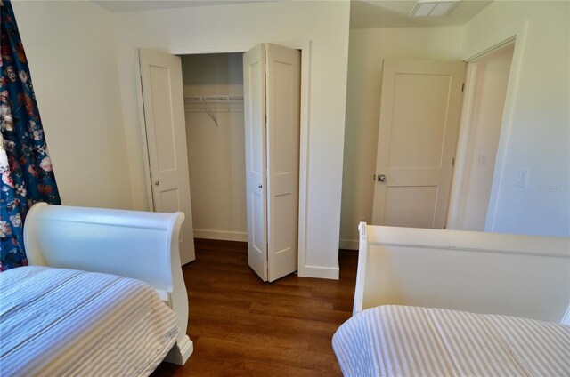 bedroom with dark wood-type flooring and a closet