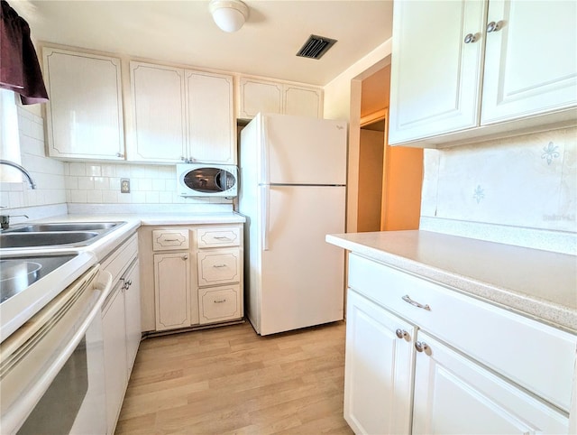 kitchen with tasteful backsplash, white appliances, light hardwood / wood-style floors, and white cabinetry