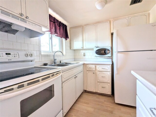 kitchen with white appliances, sink, white cabinets, light hardwood / wood-style flooring, and decorative backsplash