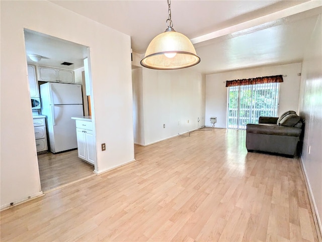 unfurnished living room with light wood-style floors, beamed ceiling, and baseboards