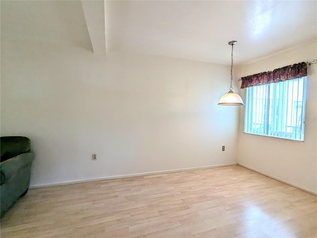 empty room featuring light wood-style floors, baseboards, and beamed ceiling