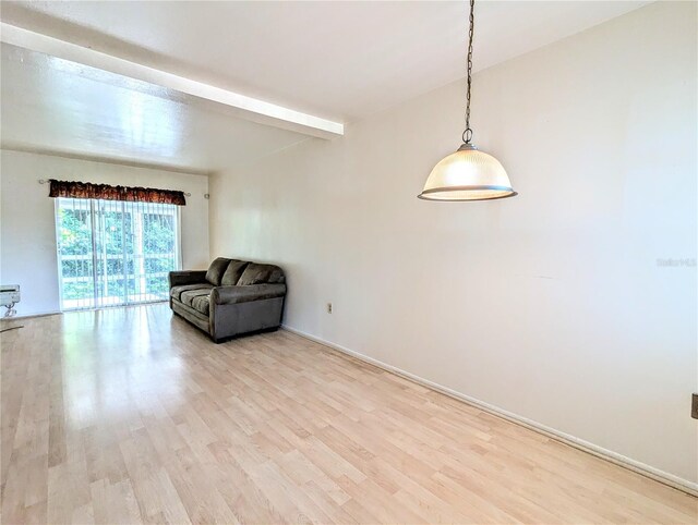 unfurnished room with light wood-type flooring and beamed ceiling