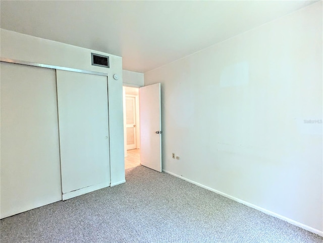 unfurnished bedroom featuring baseboards, a closet, visible vents, and carpet flooring