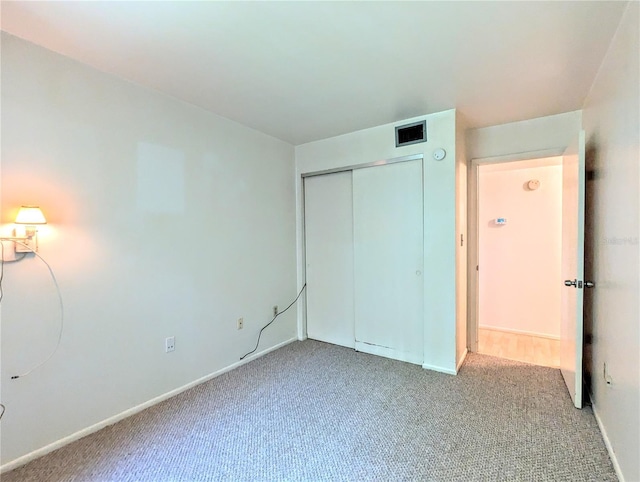 unfurnished bedroom featuring baseboards, visible vents, a closet, and carpet flooring