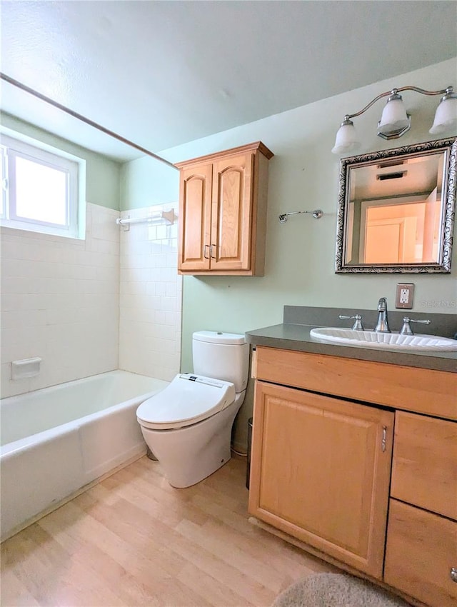 bathroom featuring shower / bathtub combination, vanity, toilet, and wood finished floors