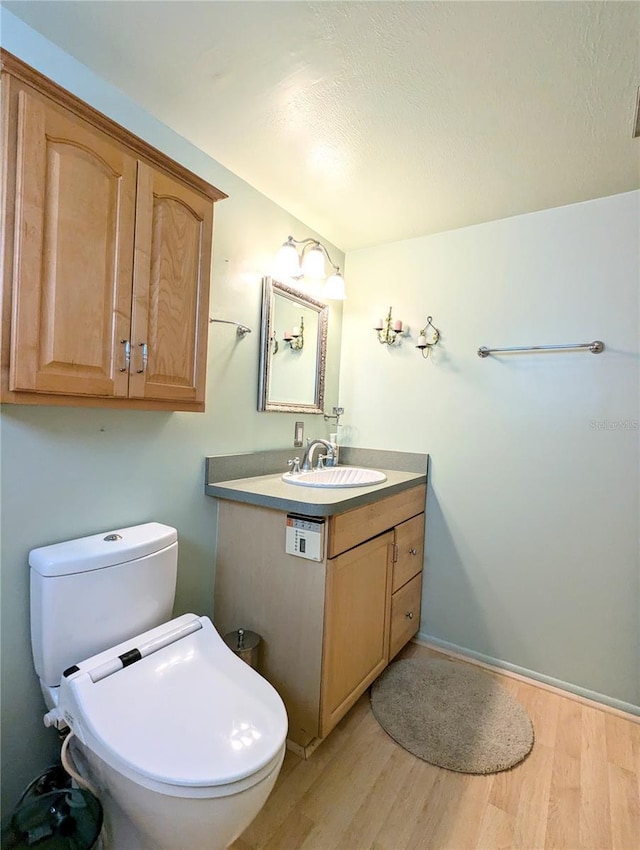 bathroom featuring toilet, wood finished floors, and vanity