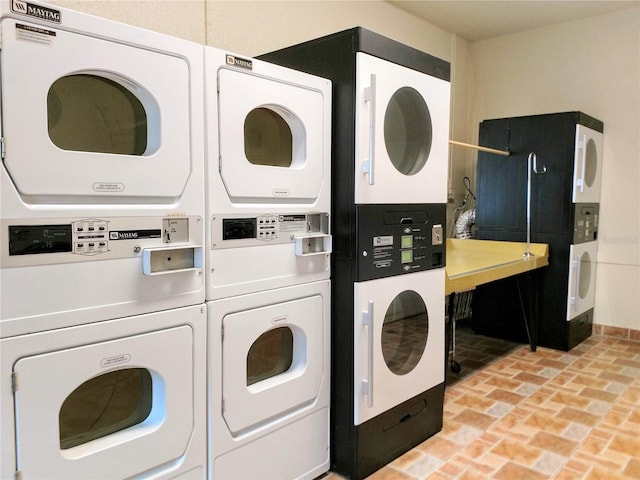 shared laundry area with brick floor, washing machine and dryer, and stacked washer / drying machine