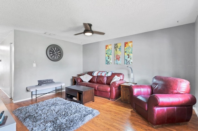 living room featuring wood-type flooring, a textured ceiling, and ceiling fan