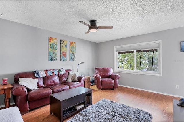 living room with a textured ceiling, ceiling fan, and light wood-type flooring