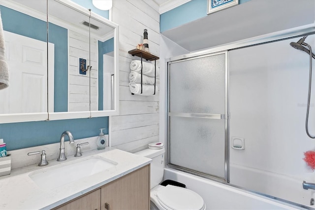 full bathroom with shower / bath combination with glass door, crown molding, toilet, vanity, and wood walls