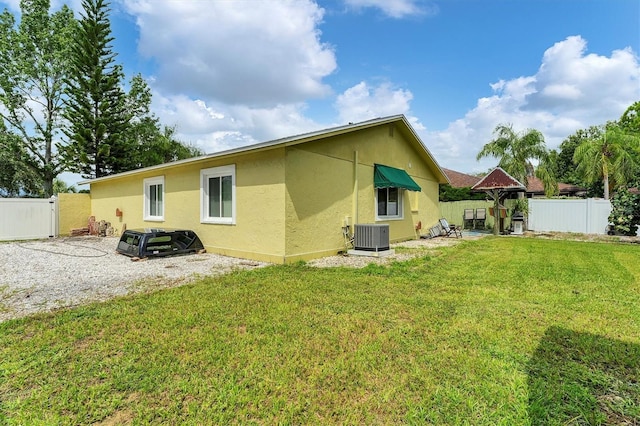 back of property with a patio area, central AC, and a yard