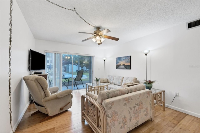 living room featuring ceiling fan, a textured ceiling, and light hardwood / wood-style flooring