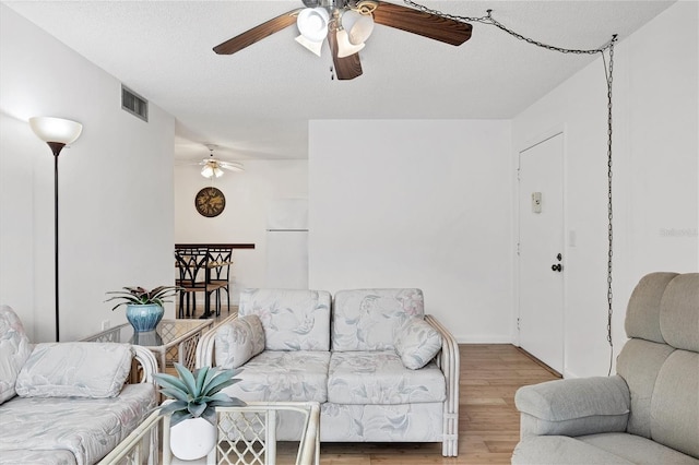 living room with light hardwood / wood-style floors, a textured ceiling, and ceiling fan