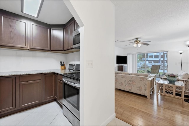 kitchen with appliances with stainless steel finishes, light stone counters, light hardwood / wood-style floors, dark brown cabinetry, and ceiling fan