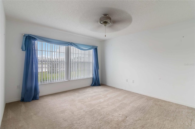 unfurnished room featuring a textured ceiling, ceiling fan, and carpet flooring