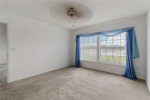 empty room with light carpet, a textured ceiling, and ceiling fan