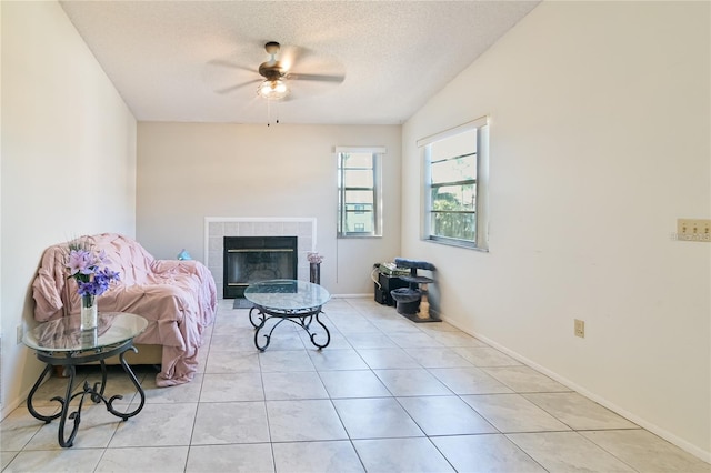 interior space featuring light tile patterned flooring, a tiled fireplace, a textured ceiling, and ceiling fan