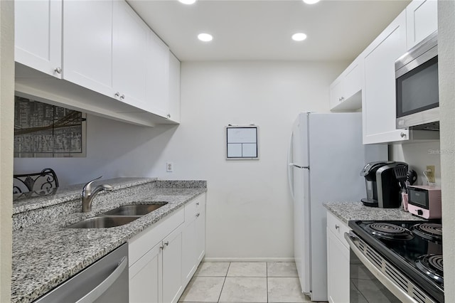 kitchen featuring light tile patterned flooring, white cabinetry, stainless steel appliances, sink, and light stone counters