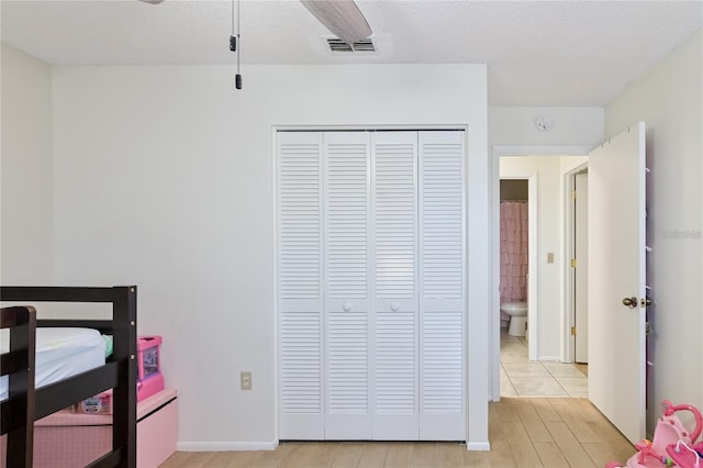 bedroom with light hardwood / wood-style floors, a closet, a textured ceiling, and ceiling fan