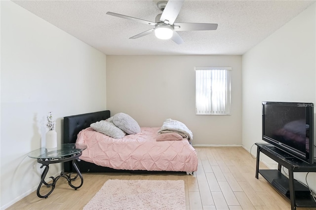 bedroom featuring light wood-type flooring, ceiling fan, and a textured ceiling