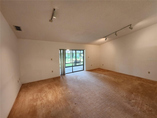 carpeted empty room featuring a textured ceiling and rail lighting