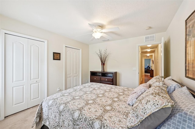 carpeted bedroom with multiple closets and ceiling fan