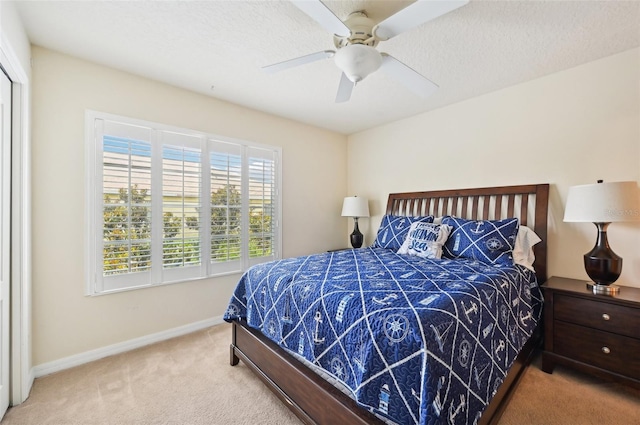 bedroom featuring light colored carpet, a textured ceiling, and ceiling fan