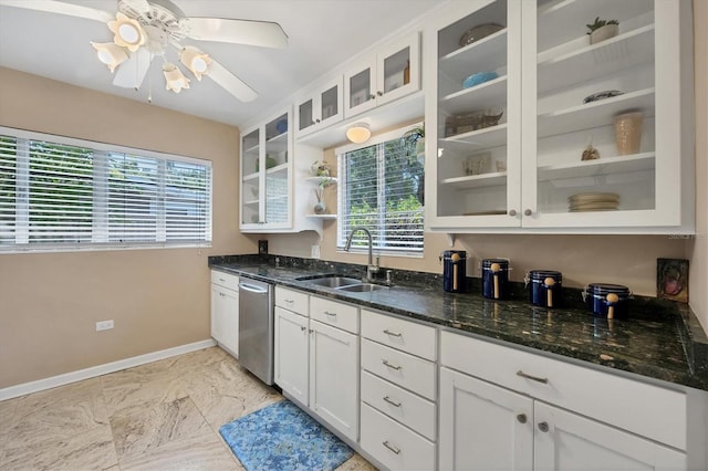 kitchen featuring stainless steel dishwasher, ceiling fan, sink, dark stone countertops, and white cabinets