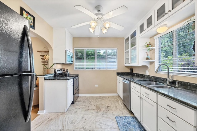 839 40th St, Sarasota, FL 34234 - kitchen with stainless steel appliances, ceiling fan, dark stone countertops, white cabinets, and glass insert cabinets