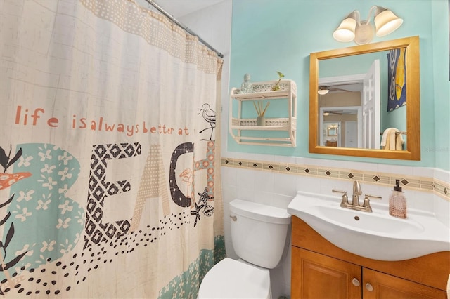 bathroom with walk in shower, vanity, tile walls, and toilet