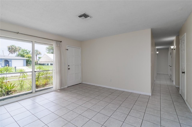 empty room with a textured ceiling and light tile patterned floors