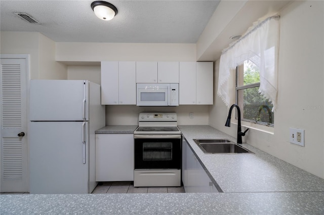 kitchen featuring sink, white cabinets, white appliances, light tile patterned floors, and a textured ceiling