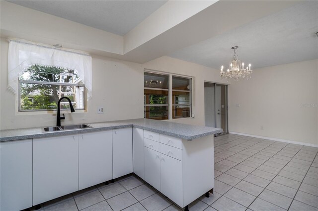 kitchen with light tile patterned flooring, decorative light fixtures, white cabinetry, sink, and kitchen peninsula