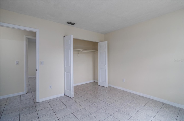 unfurnished bedroom featuring light tile patterned floors, a textured ceiling, and a closet