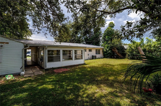 back of house with central AC unit and a lawn