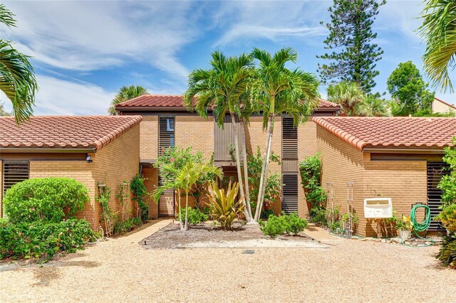 mediterranean / spanish-style house featuring a tile roof and brick siding