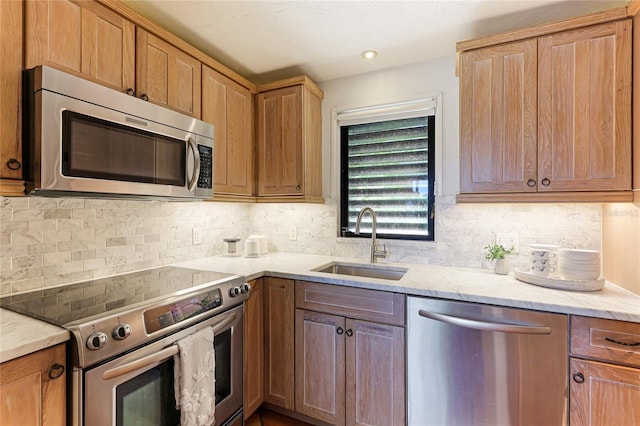 kitchen featuring brown cabinetry, decorative backsplash, stainless steel appliances, a sink, and recessed lighting