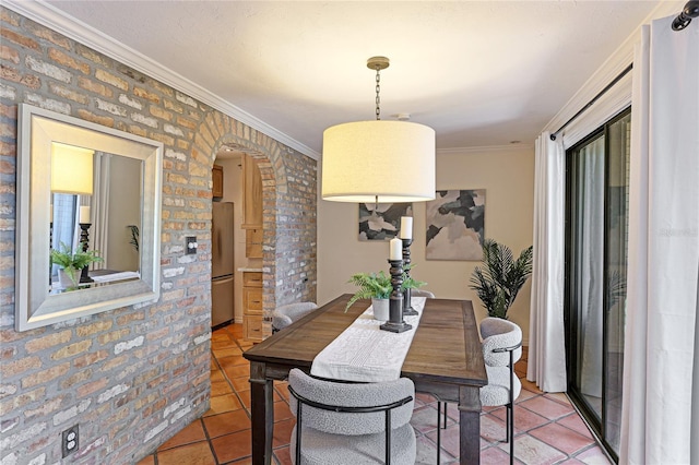 dining area with ornamental molding, arched walkways, brick wall, and light tile patterned floors