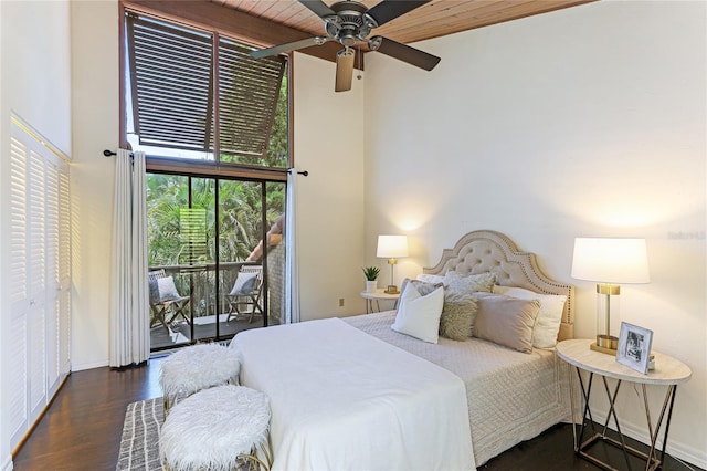 bedroom featuring baseboards, a ceiling fan, dark wood-style flooring, access to exterior, and a high ceiling