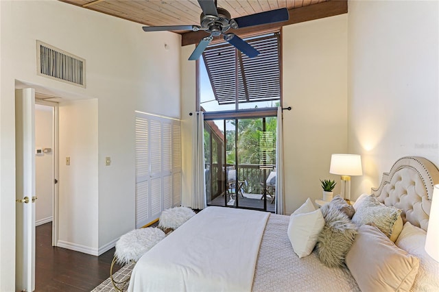 bedroom with baseboards, visible vents, a towering ceiling, dark wood-style flooring, and access to exterior