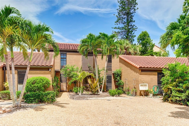 mediterranean / spanish-style home featuring brick siding and a tiled roof