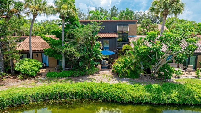 view of front of property featuring a patio area, a water view, and a tiled roof