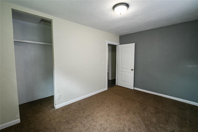 unfurnished bedroom featuring a closet and dark carpet