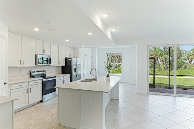 kitchen with an island with sink, appliances with stainless steel finishes, sink, and white cabinets