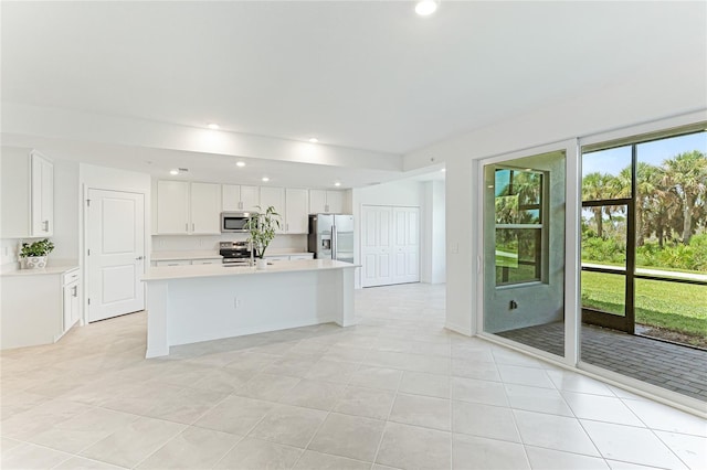 kitchen with white cabinetry, stainless steel appliances, an island with sink, and light tile patterned floors