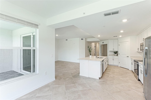 kitchen with light tile patterned flooring, an island with sink, sink, white cabinets, and stainless steel appliances