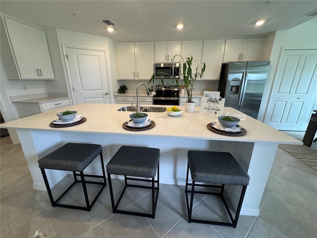 17445 Opal Sand Dr Unit 104, Venice, FL 34293 - kitchen with stainless steel appliances, a sink, white cabinetry, a kitchen breakfast bar, and a center island with sink